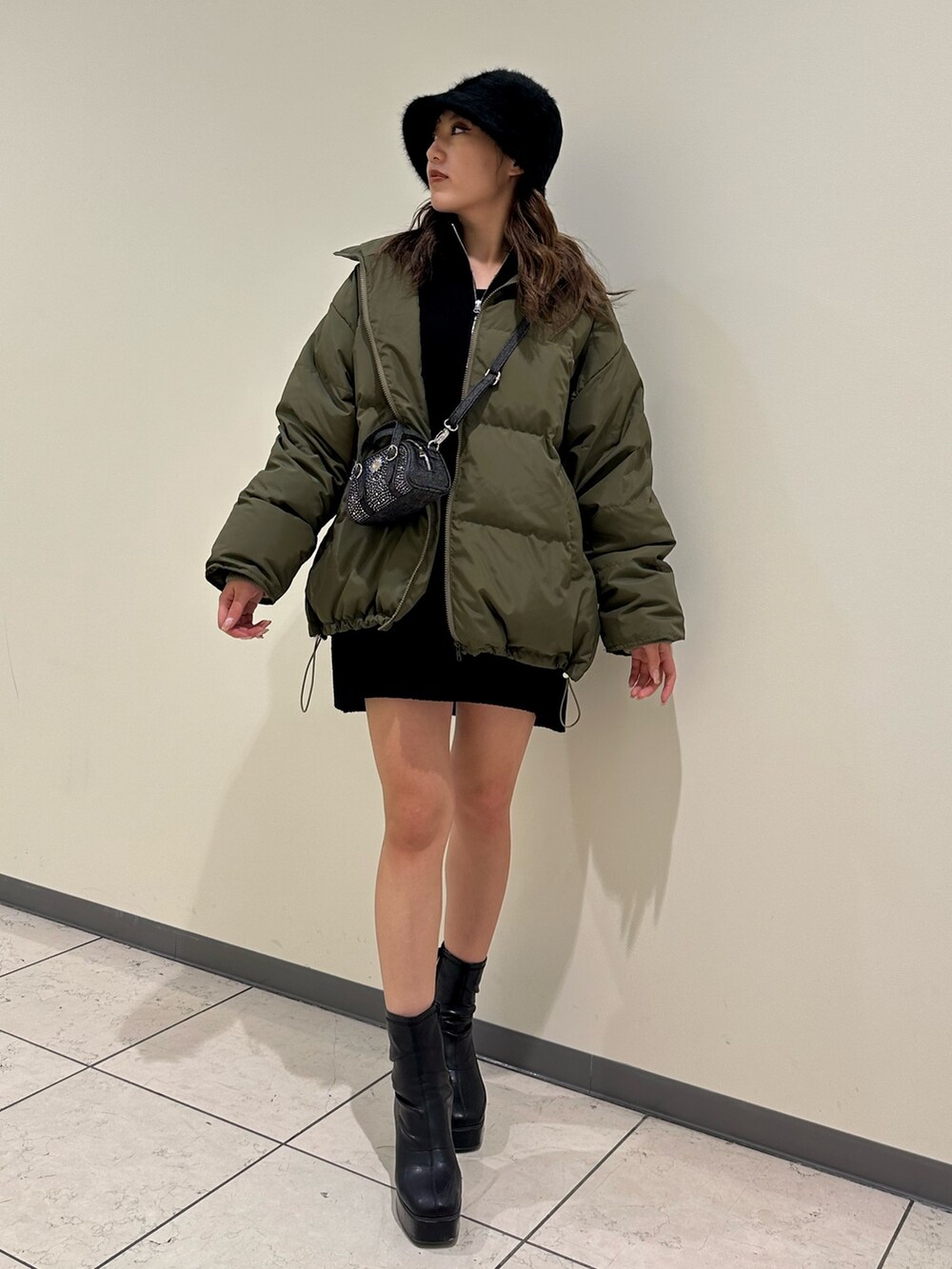 ブラック系のブーツ、ブラック系のニット/セーター、グリーン系のダウンジャケット/コートを着用したレディースの冬コーディネートの2枚目の写真