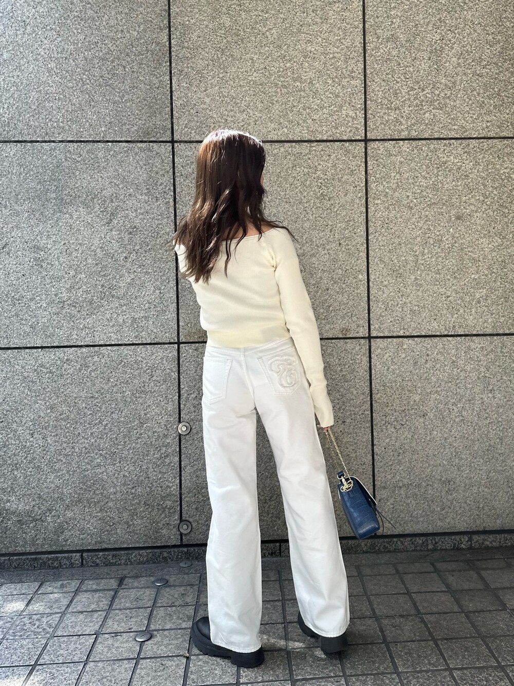 ホワイト系のニット/セーター、ホワイト系のデニムパンツ、ブルー系のショルダーバッグを着用したレディースの春コーディネートの3枚目の写真