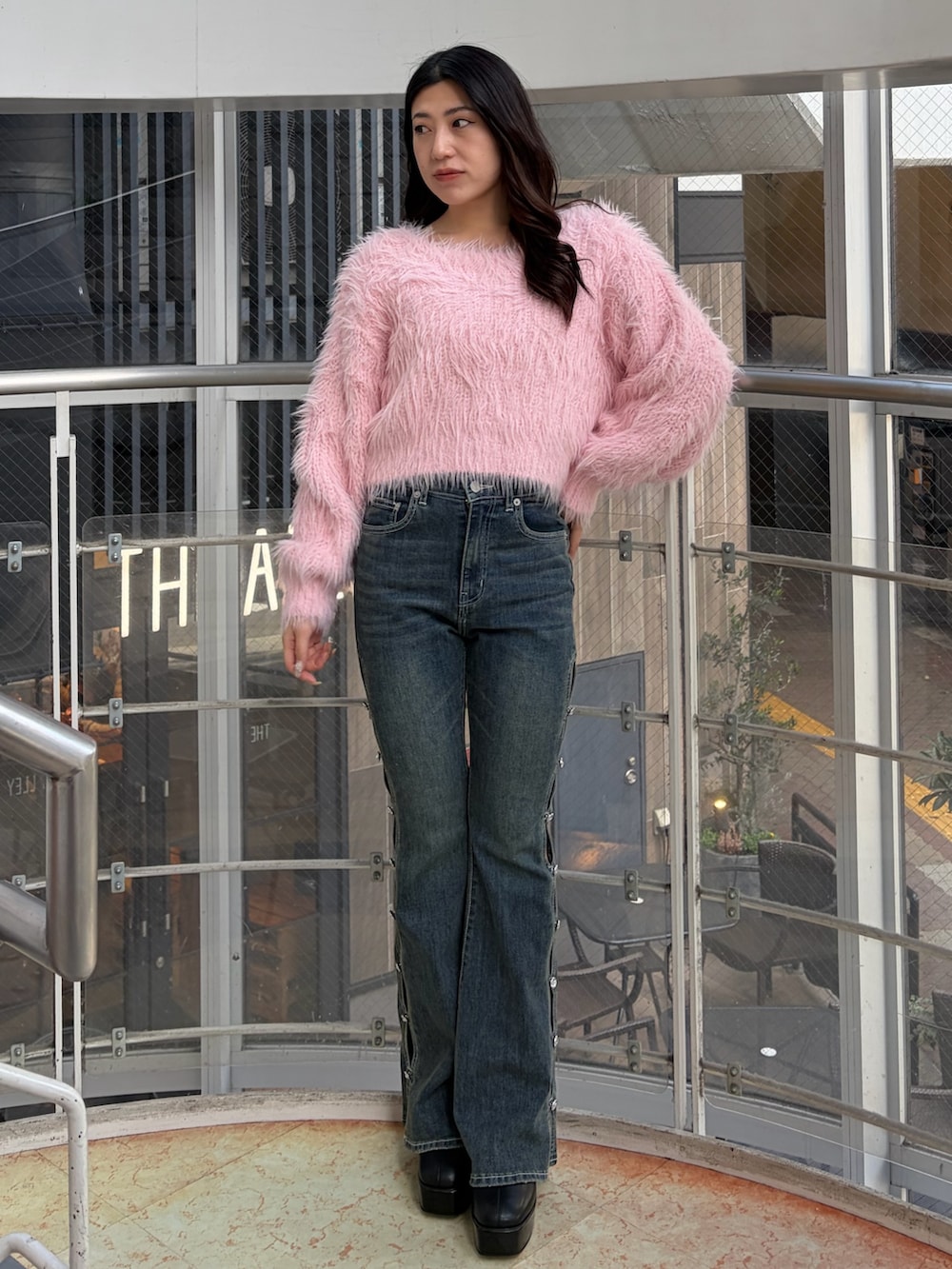 ブルー系のデニムパンツ、ピンク系のニット/セーター、ブラック系のブーツを着用したレディースの冬コーディネートの3枚目の写真