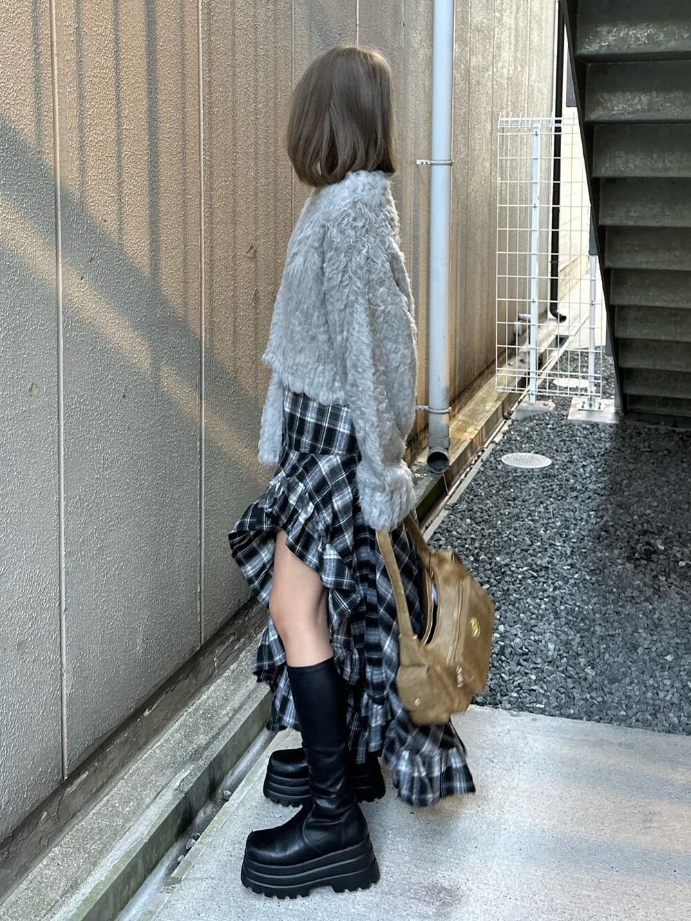 グレー系のニット/セーター、ブラック系のスカート、ブラック系のブーツを着用したレディースの冬コーディネートの3枚目の写真