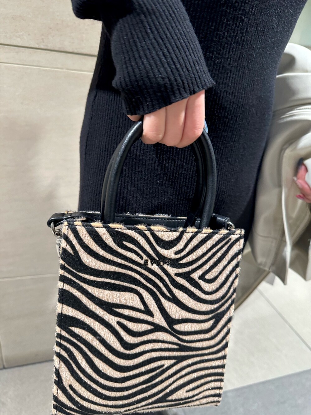 ブラック系のワンピース、ホワイト系のライダースジャケット、その他のショルダーバッグを着用したレディースの冬コーディネートの7枚目の写真