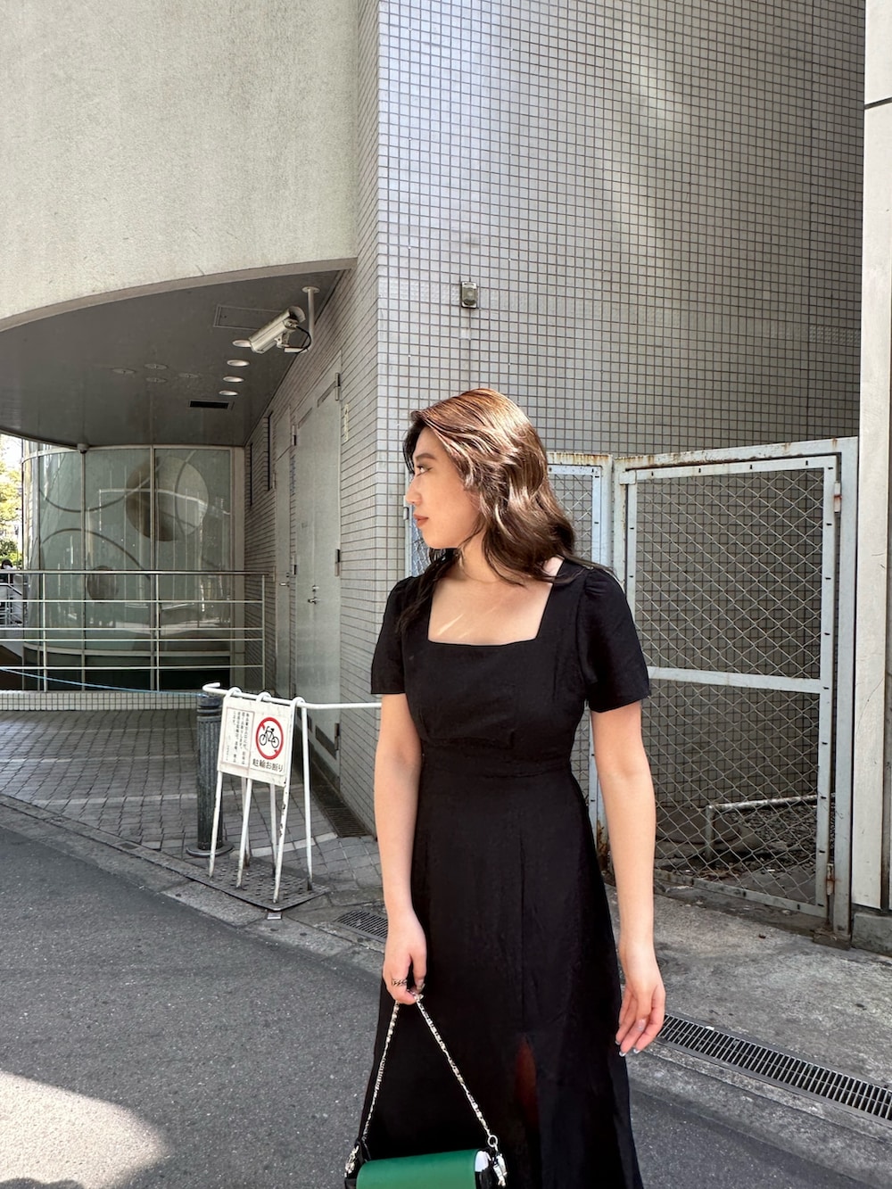 ブラック系のワンピース、ホワイト系のブーツ、ブラック系のショルダーバッグを着用したレディースの春コーディネートの4枚目の写真
