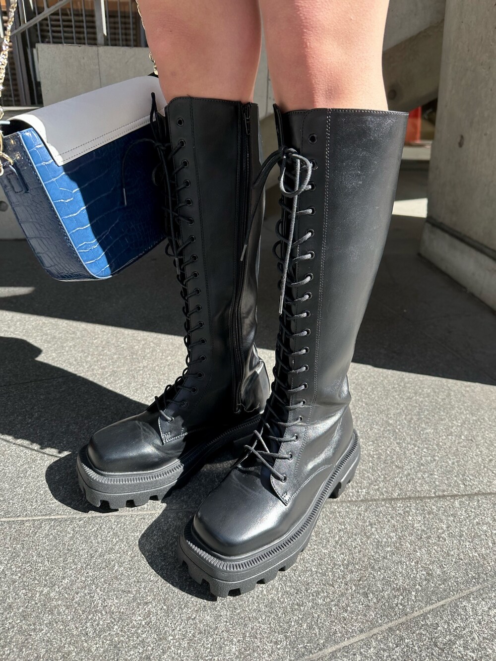 ブラック系のスウェット、ブラック系のブーツ、ブルー系のショルダーバッグを着用したレディースの冬コーディネートの7枚目の写真