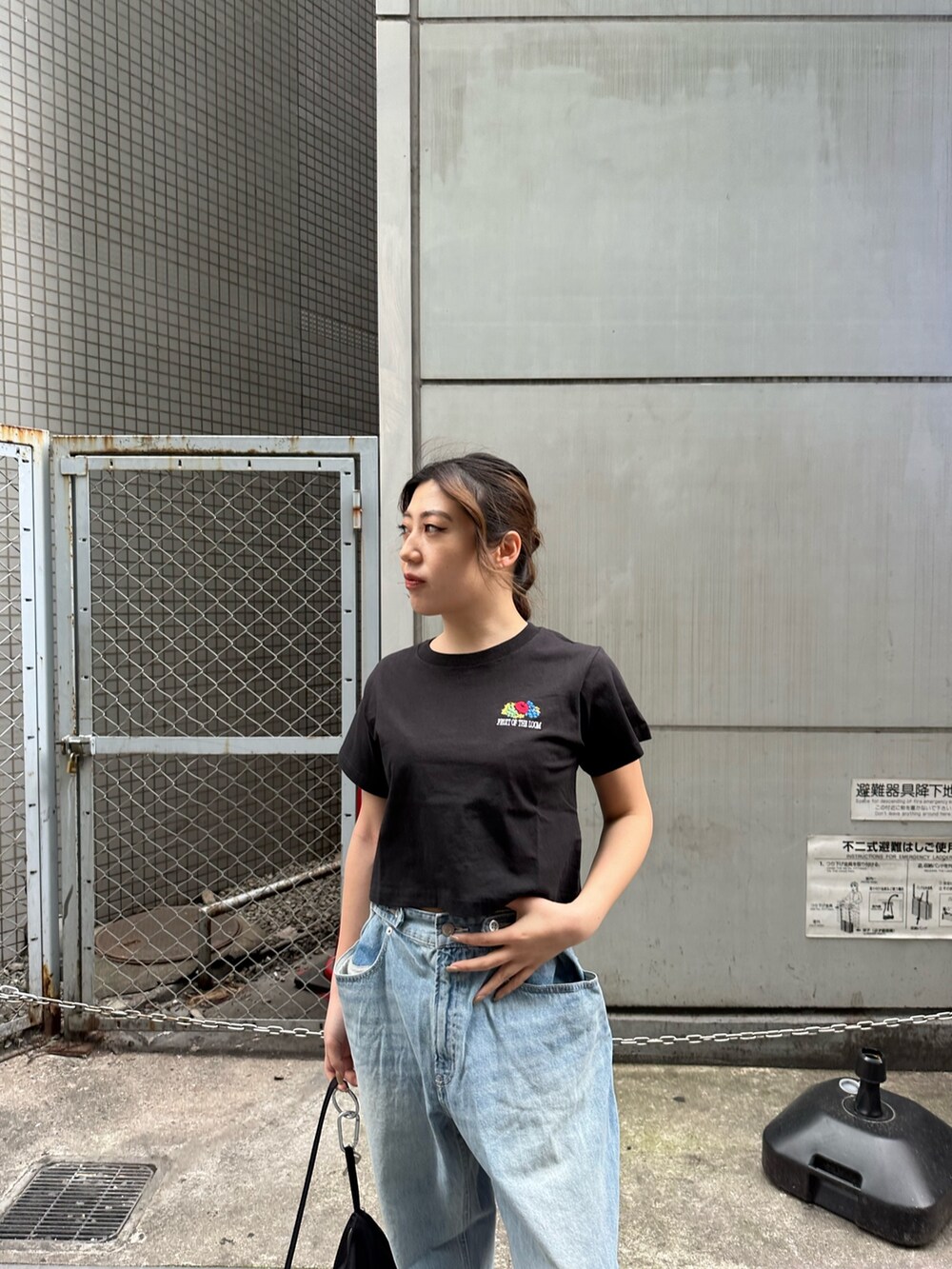 ブラック系のTシャツ/カットソー、ブラック系のスニーカー、ブルー系のデニムパンツを着用したレディースの春コーディネートの4枚目の写真
