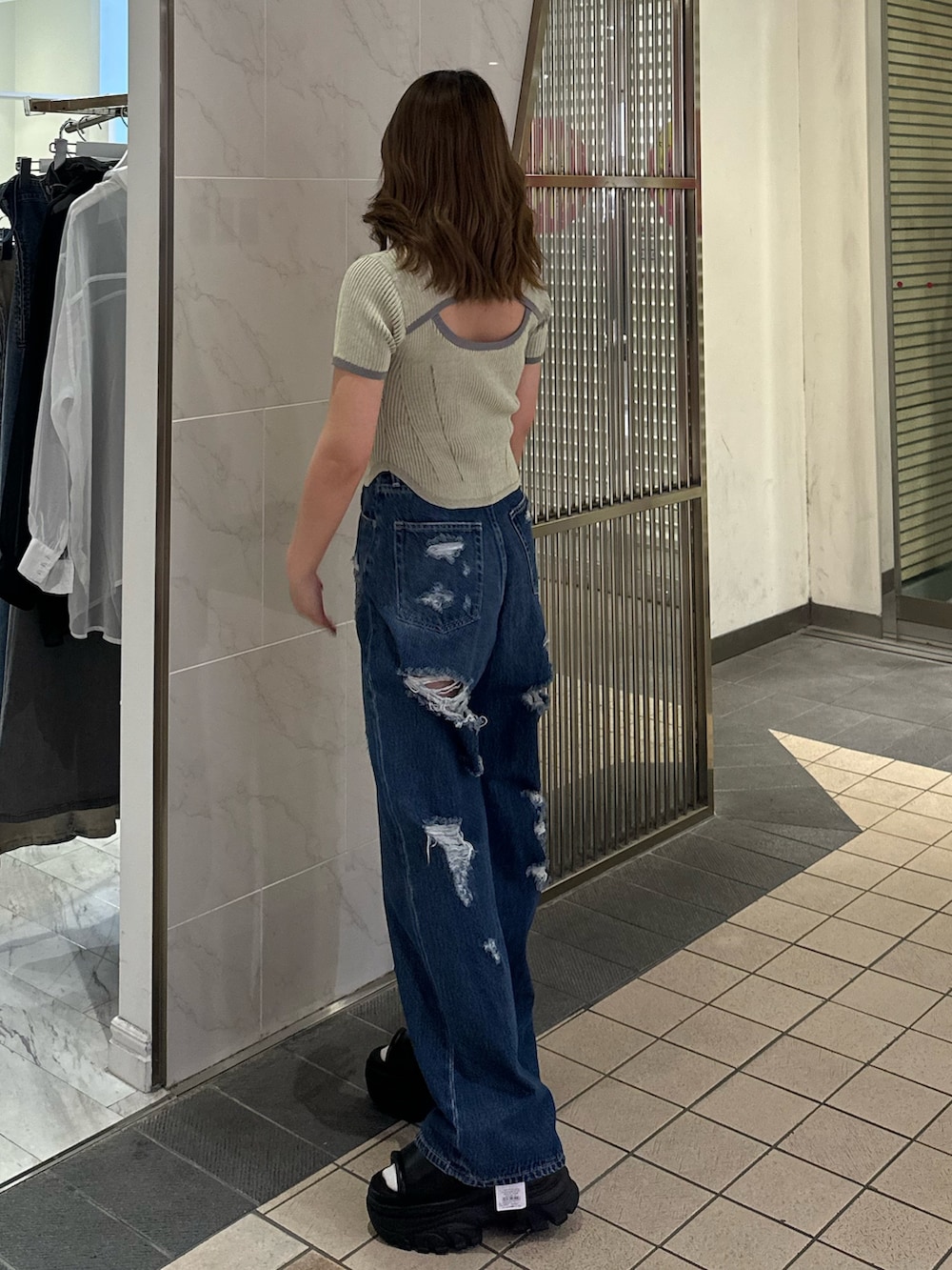 ブルー系のデニムパンツ、ブラック系のサンダル、イエロー系のニット/セーターを着用したレディースの春コーディネートの2枚目の写真