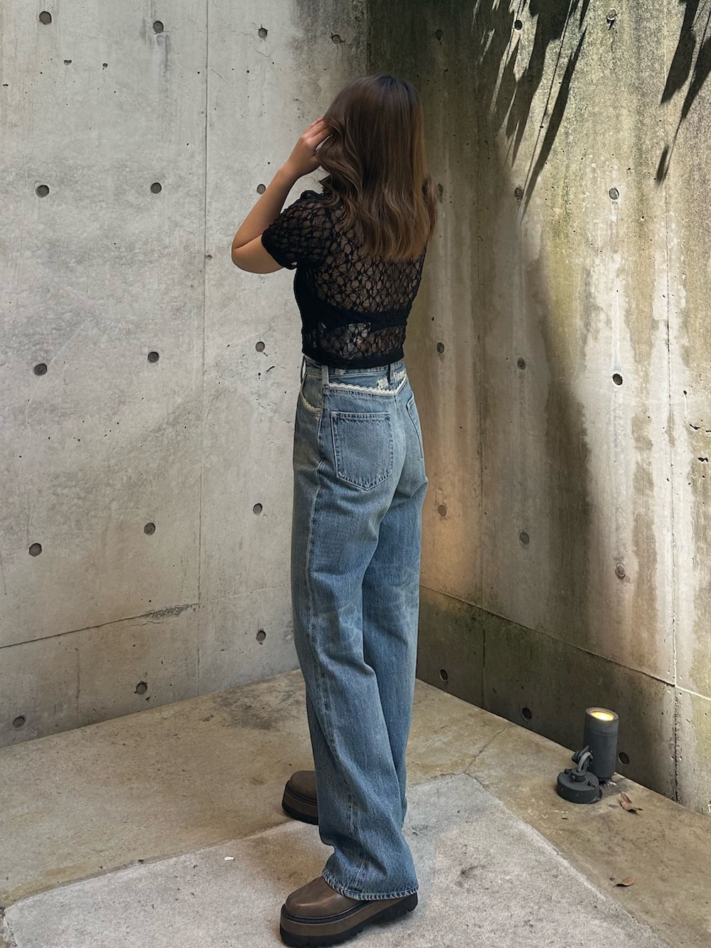 ブルー系のデニムパンツ、ブラウン系のブーツ、ブラック系のTシャツ/カットソーを着用したレディースの春コーディネートの3枚目の写真