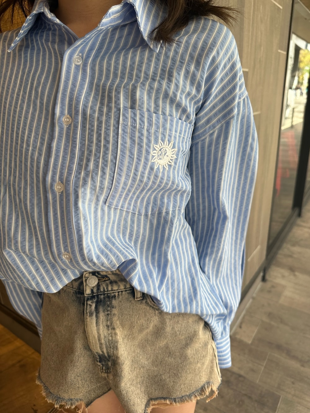 ブルー系のシャツ/ブラウス、ブラック系のブーツ、ベージュ系のデニムパンツを着用したレディースの春コーディネートの6枚目の写真