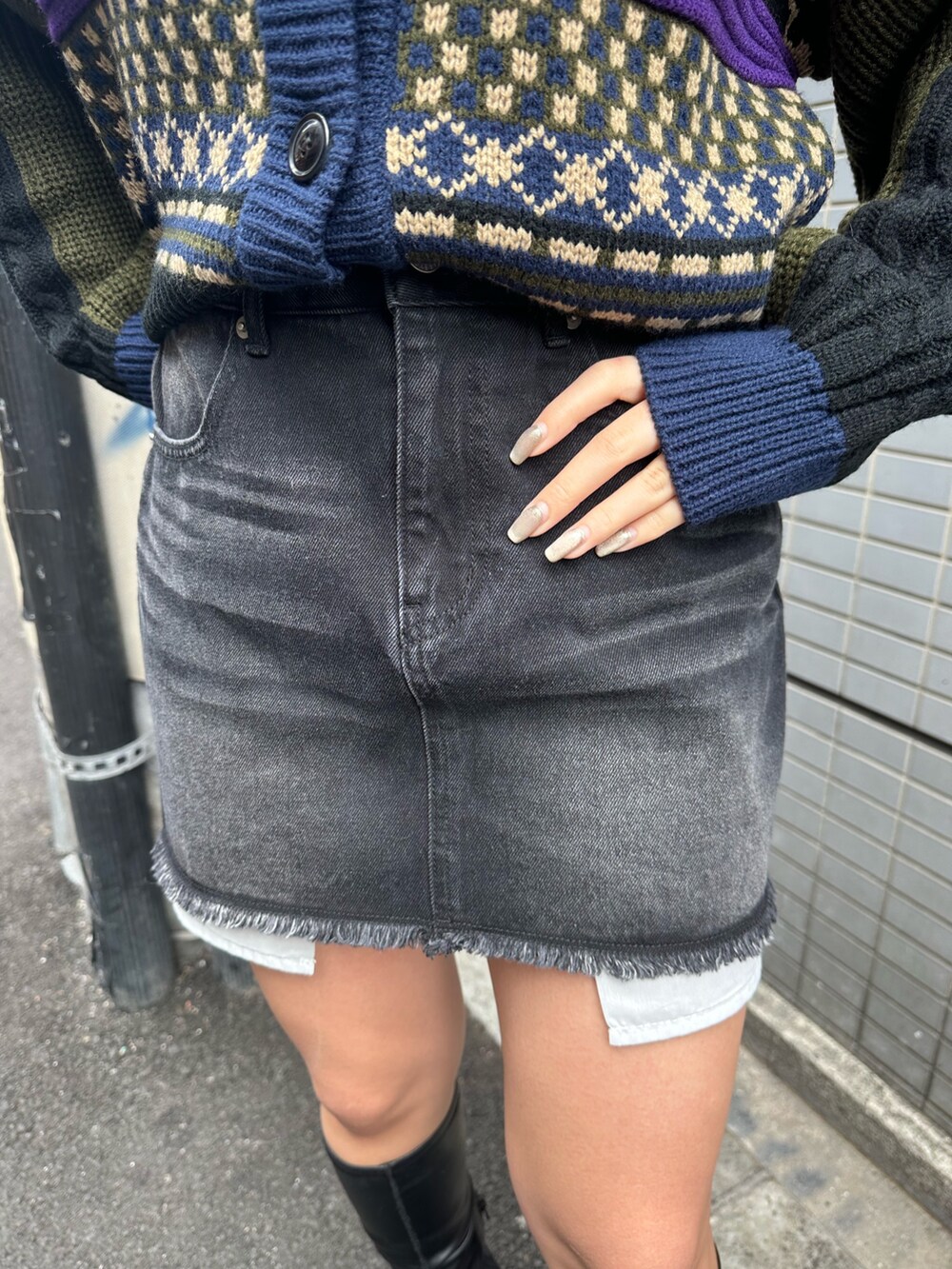 ブラック系のブーツ、ベージュ系のニット/セーター、ブラック系のデニムスカートを着用したレディースの冬コーディネートの6枚目の写真