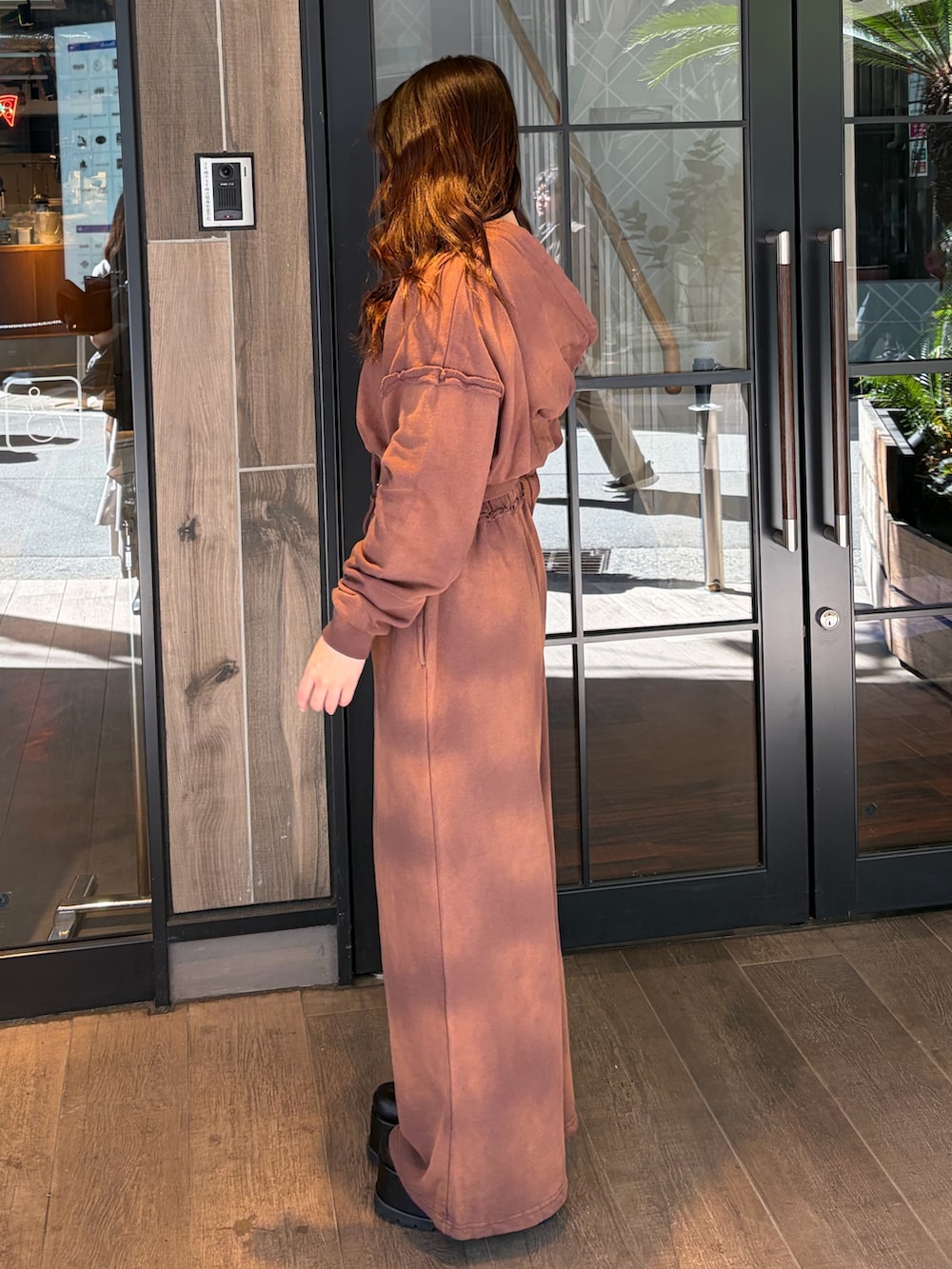 ブラウン系のスウェットパンツ、ブラウン系のパーカー、ブラック系のブーツを着用したレディースの春コーディネートの2枚目の写真