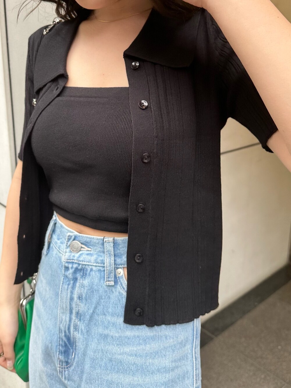 ブラック系のニット/セーター、ブルー系のデニムパンツ、グリーン系のショルダーバッグを着用したレディースの春コーディネートの4枚目の写真