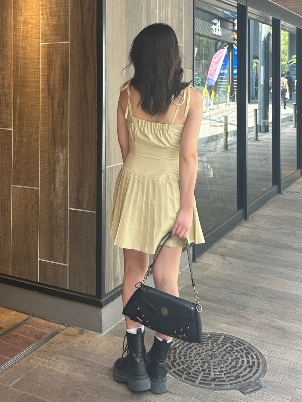 イエロー系のワンピース、ブラック系のブーツ、ブラック系のハンドバッグを着用したレディースの夏コーディネートの3枚目の写真