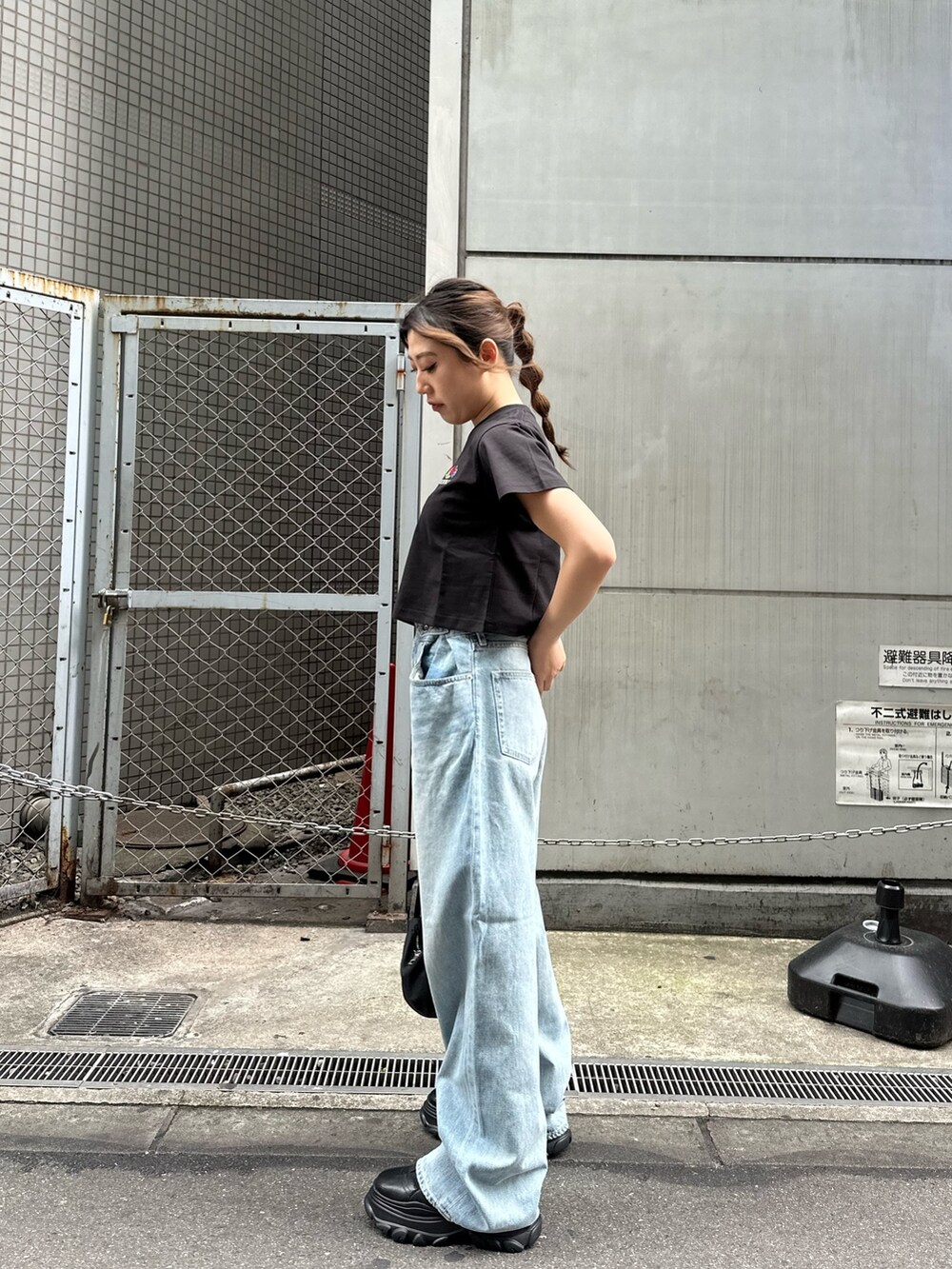 ブラック系のTシャツ/カットソー、ブラック系のスニーカー、ブルー系のデニムパンツを着用したレディースの春コーディネートの3枚目の写真