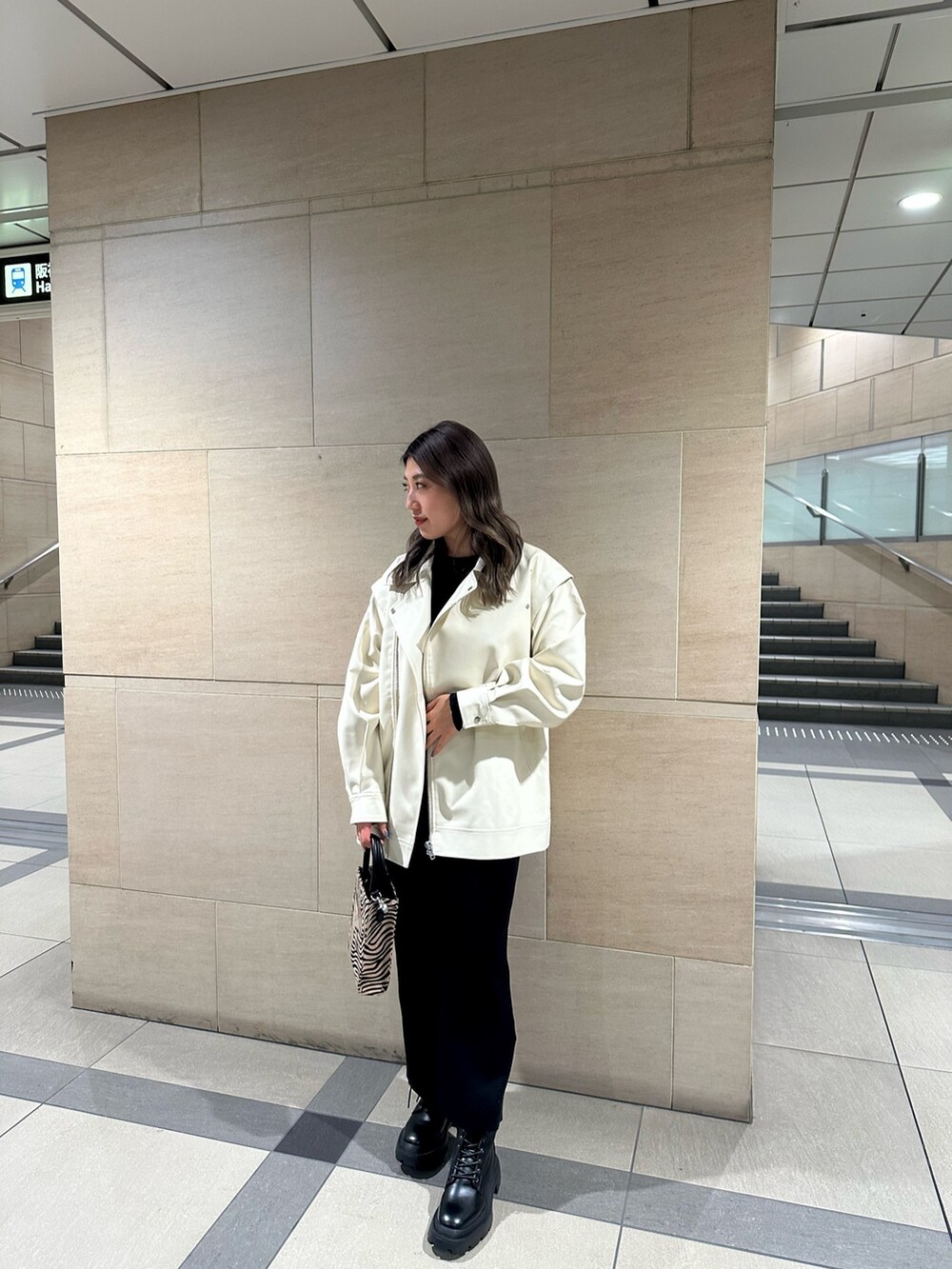 ブラック系のワンピース、ホワイト系のライダースジャケット、その他のショルダーバッグを着用したレディースの冬コーディネートの2枚目の写真