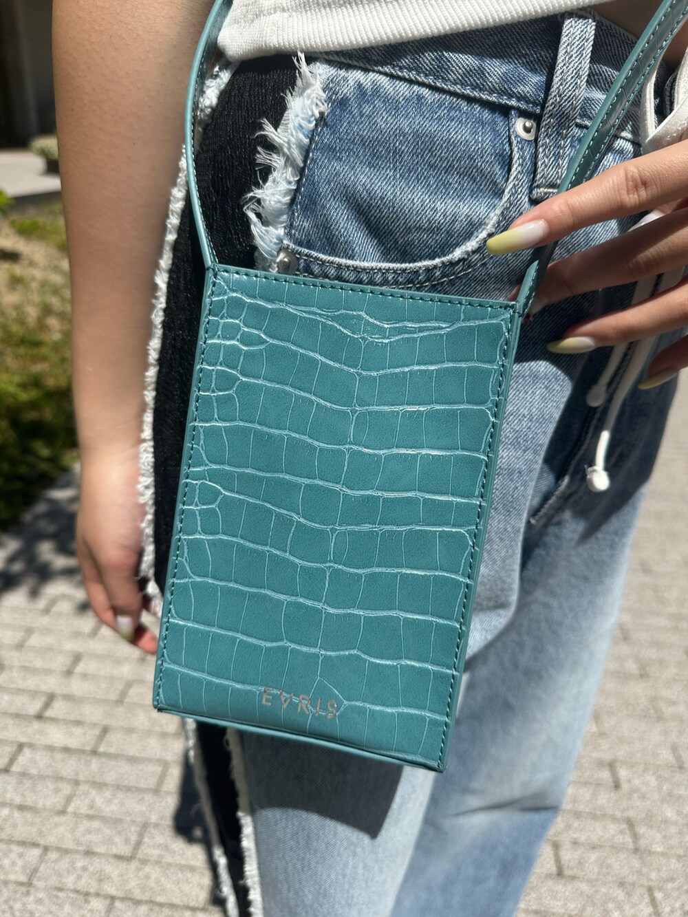 ホワイト系のタンクトップ、ホワイト系のサンダル、ブルー系のデニムパンツを着用したレディースの夏コーディネートの8枚目の写真