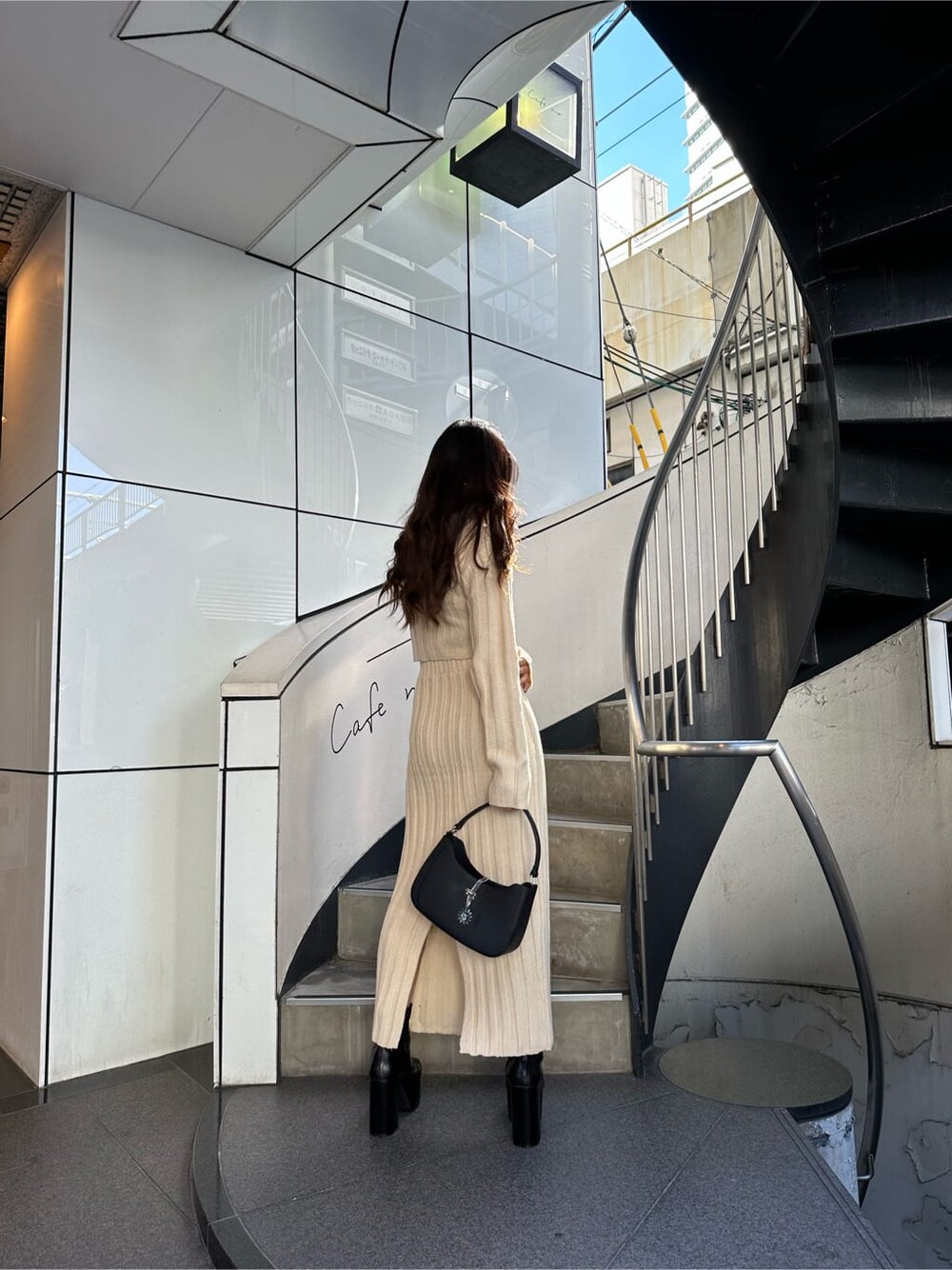 ホワイト系のスカート、ホワイト系のニット/セーター、ブラック系のハンドバッグを着用したレディースの秋コーディネートの2枚目の写真