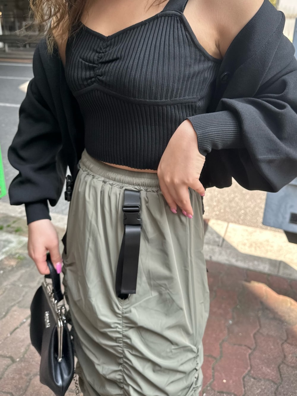 ベージュ系のスカート、ブラック系のカーディガン/ボレロ、ブラック系のショルダーバッグを着用したレディースの春コーディネートの5枚目の写真