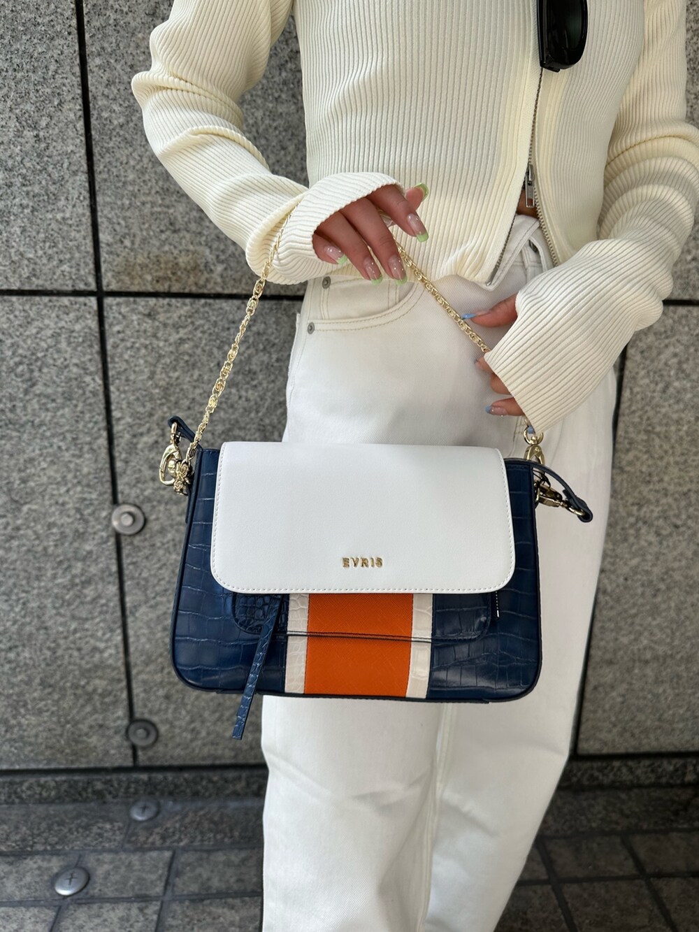 ホワイト系のニット/セーター、ホワイト系のデニムパンツ、ブルー系のショルダーバッグを着用したレディースの春コーディネートの8枚目の写真