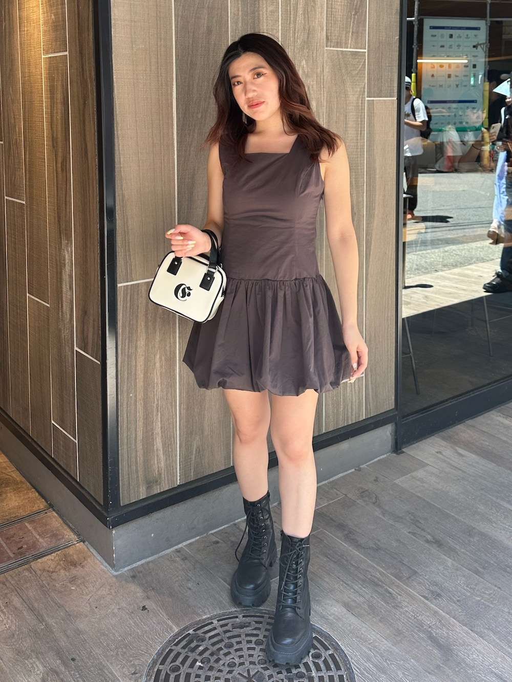 グレー系のワンピース、ホワイト系のショルダーバッグ、ブラック系のブーツを着用したレディースの夏コーディネートの2枚目の写真