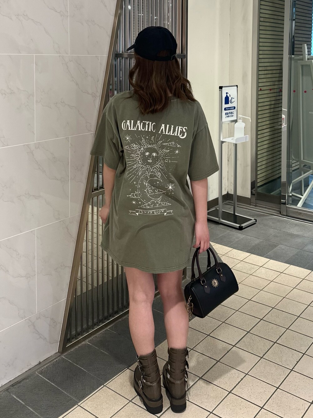 ブラック系のショルダーバッグ、ブラウン系のブーツ、グリーン系のTシャツ/カットソーを着用したレディースの春コーディネートの3枚目の写真