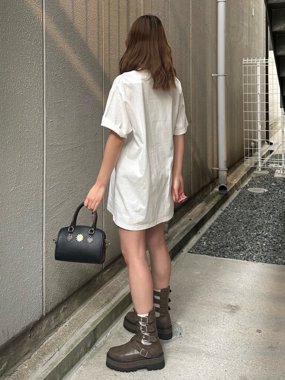 ホワイト系のTシャツ/カットソー、ブラック系のショルダーバッグ、ブラウン系のブーツを着用したレディースの夏コーディネートの2枚目の写真