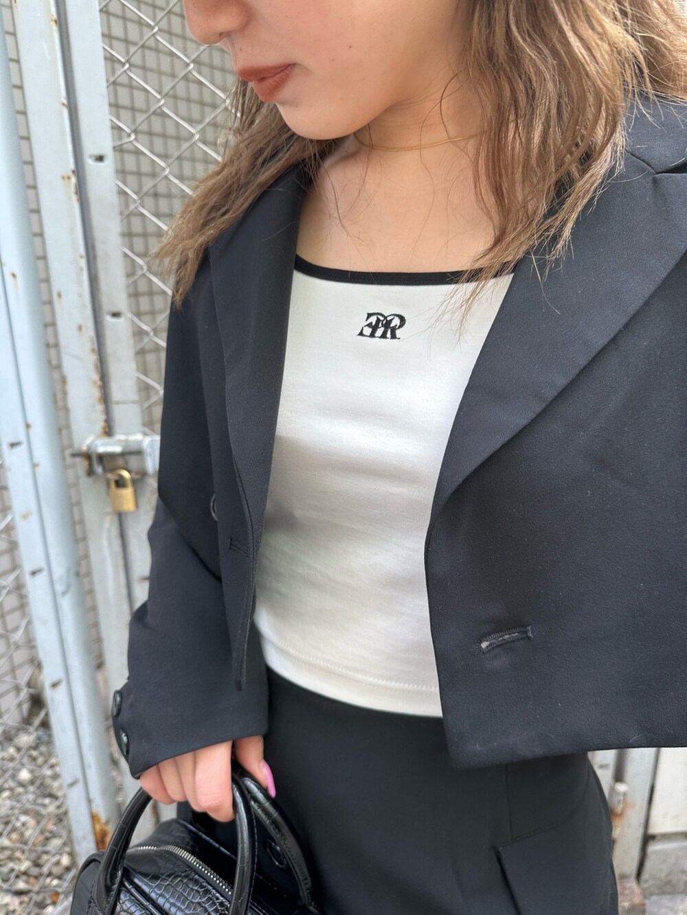 ホワイト系のTシャツ/カットソー、ブラック系のテーラードジャケット、ブラック系のスカートを着用したレディースの春コーディネートの5枚目の写真