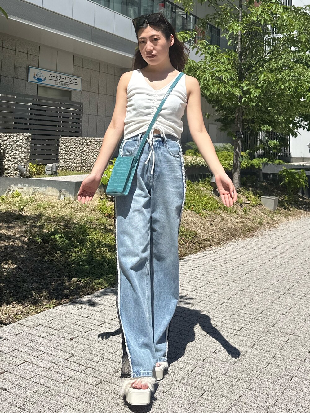 ホワイト系のタンクトップ、ホワイト系のサンダル、ブルー系のデニムパンツを着用したレディースの夏コーディネートの2枚目の写真