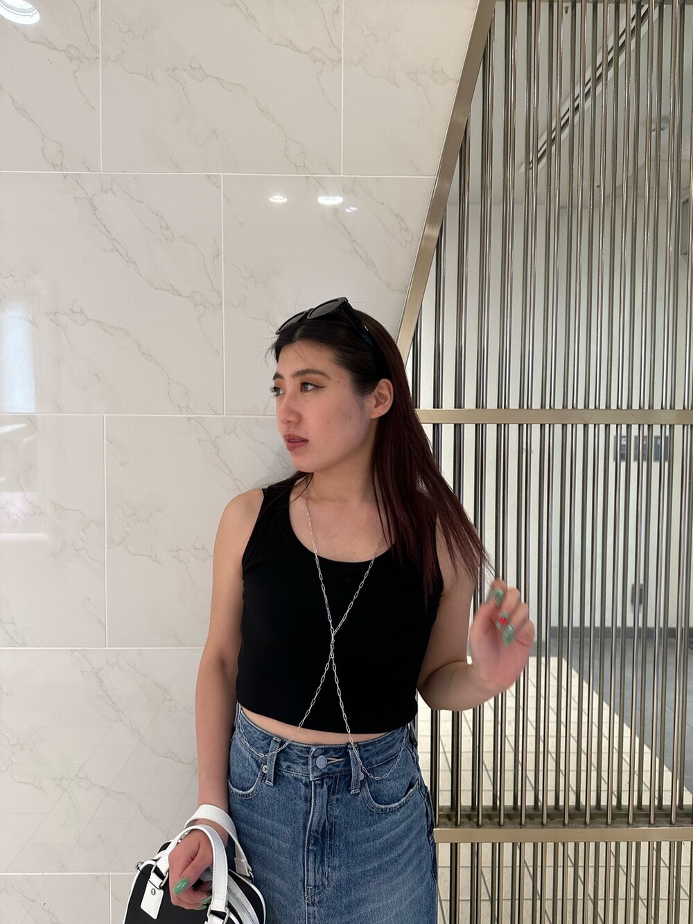 ブルー系のデニムスカート、ブラック系のタンクトップ、ブラック系のサンダルを着用したレディースの春コーディネートの5枚目の写真