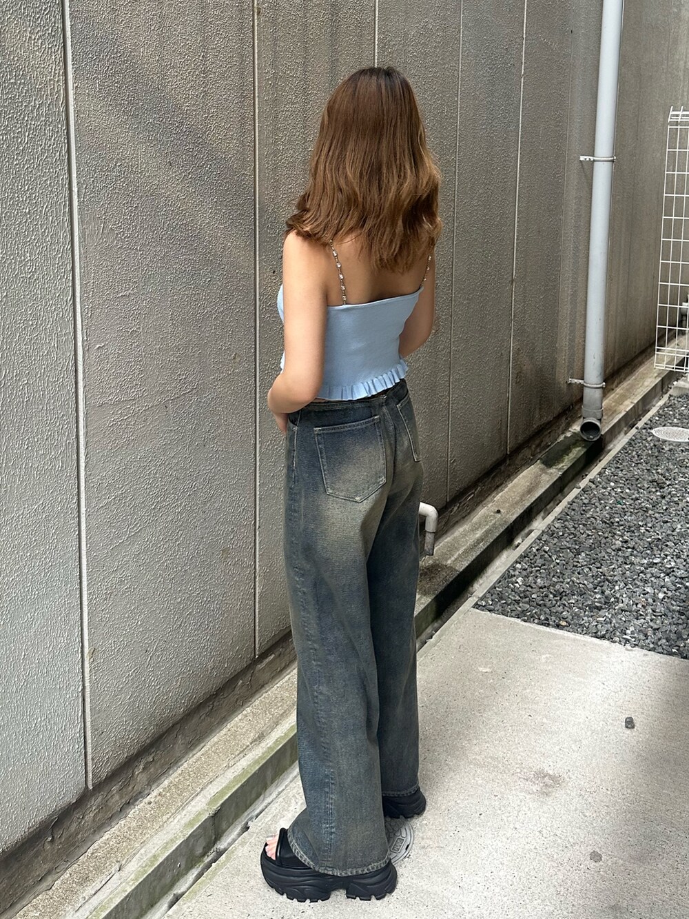 ブルー系のデニムパンツ、ブラック系のサンダル、ブルー系のキャミソールを着用したレディースの夏コーディネートの2枚目の写真
