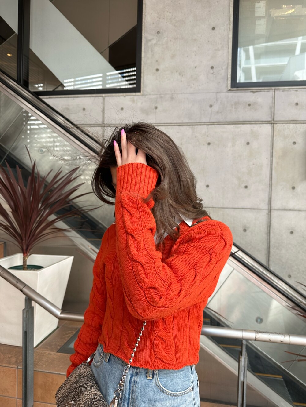 オレンジ系のカーディガン/ボレロ、ホワイト系のシャツ/ブラウス、ブルー系のデニムパンツを着用したレディースの冬コーディネートの4枚目の写真