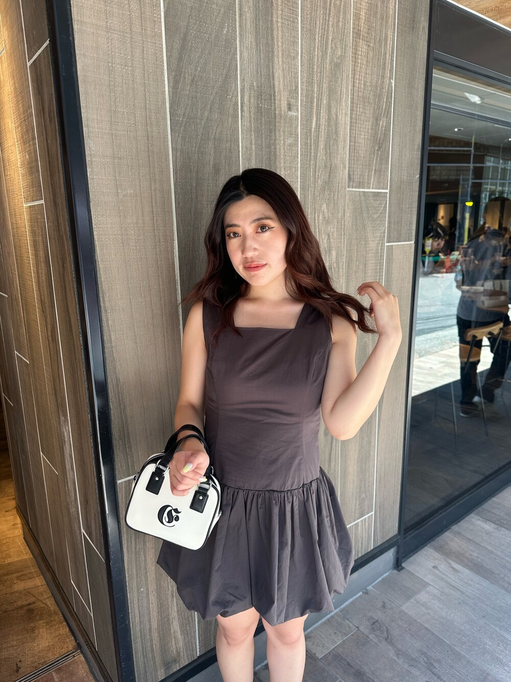 グレー系のワンピース、ホワイト系のショルダーバッグ、ブラック系のブーツを着用したレディースの夏コーディネートの6枚目の写真