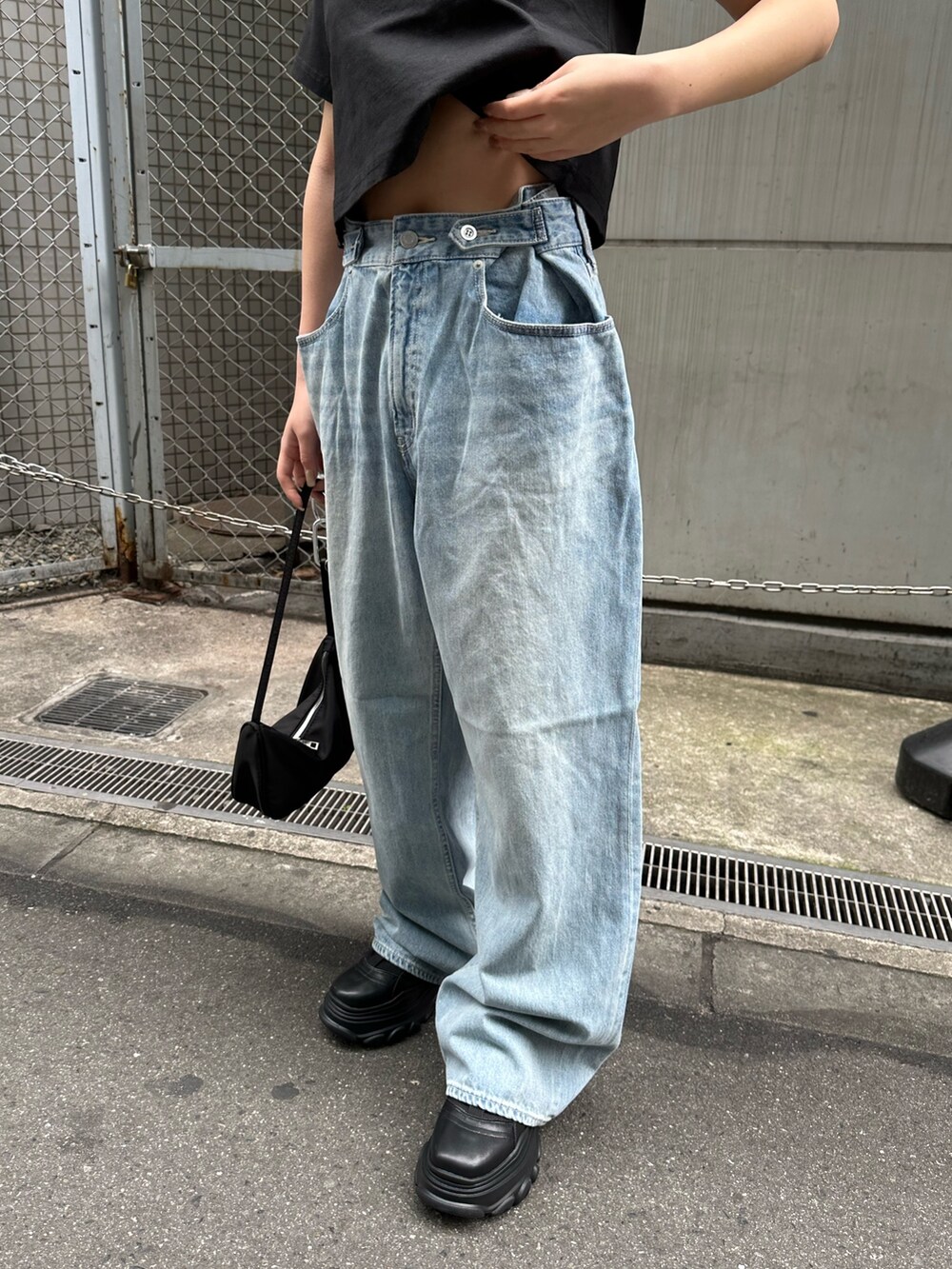 ブラック系のTシャツ/カットソー、ブラック系のスニーカー、ブルー系のデニムパンツを着用したレディースの春コーディネートの6枚目の写真