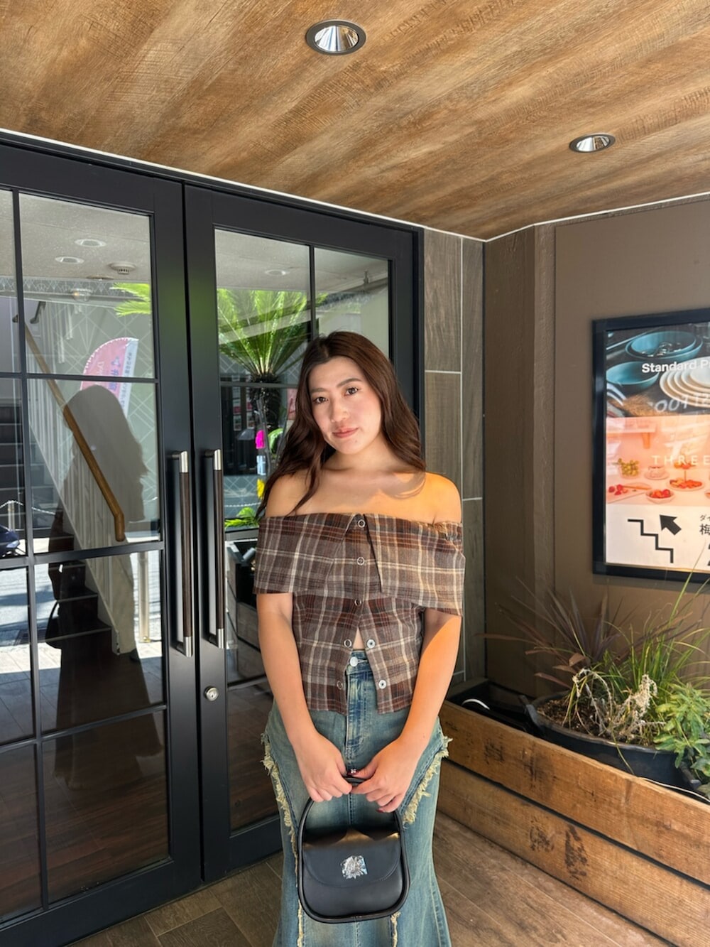 ブラック系のハンドバッグ、ブラック系のサンダル、ブルー系のデニムスカートを着用したレディースの夏コーディネートの4枚目の写真