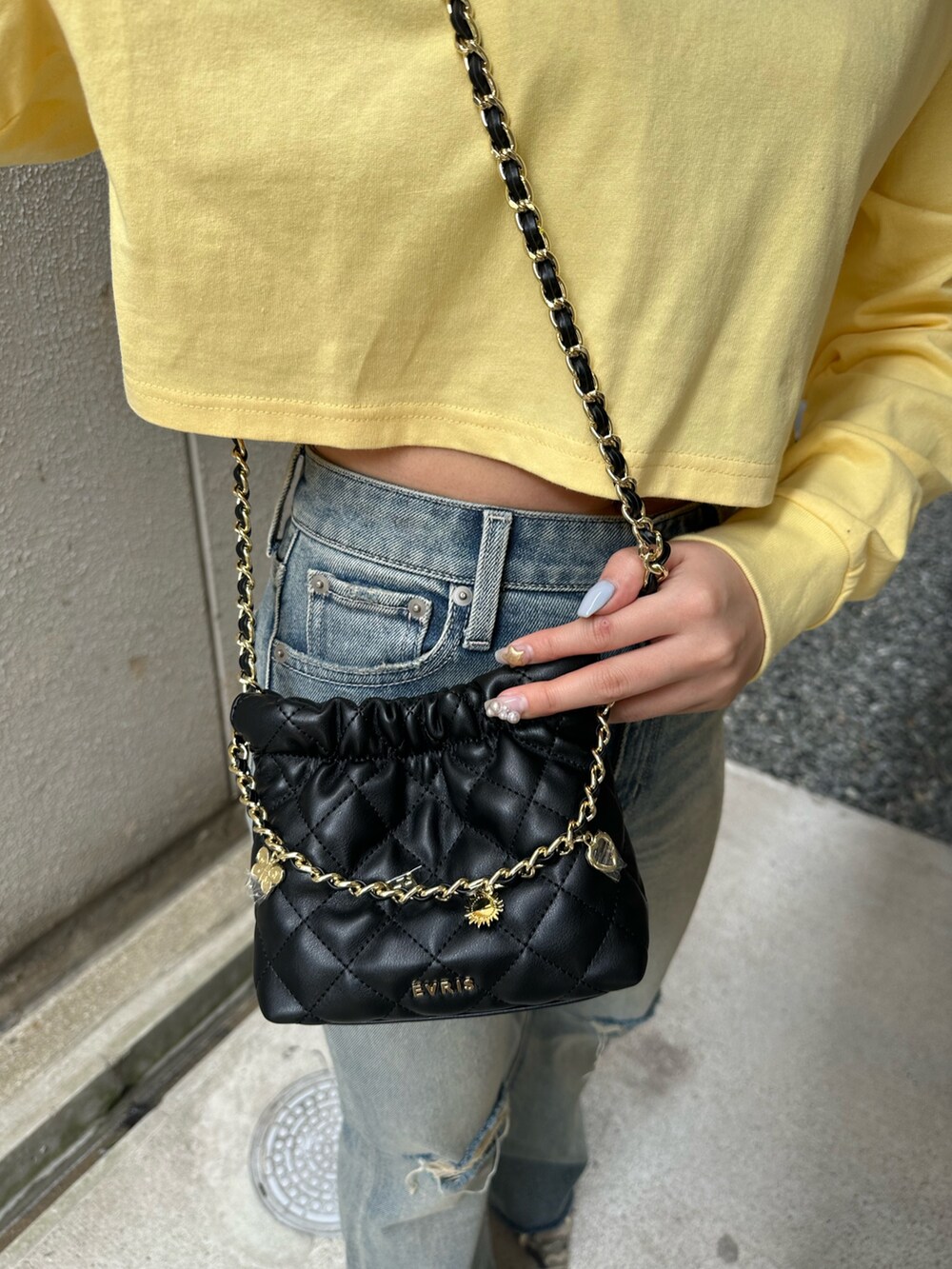 イエロー系のTシャツ/カットソー、ブルー系のデニムパンツ、ブラック系のショルダーバッグを着用したレディースの春コーディネートの6枚目の写真