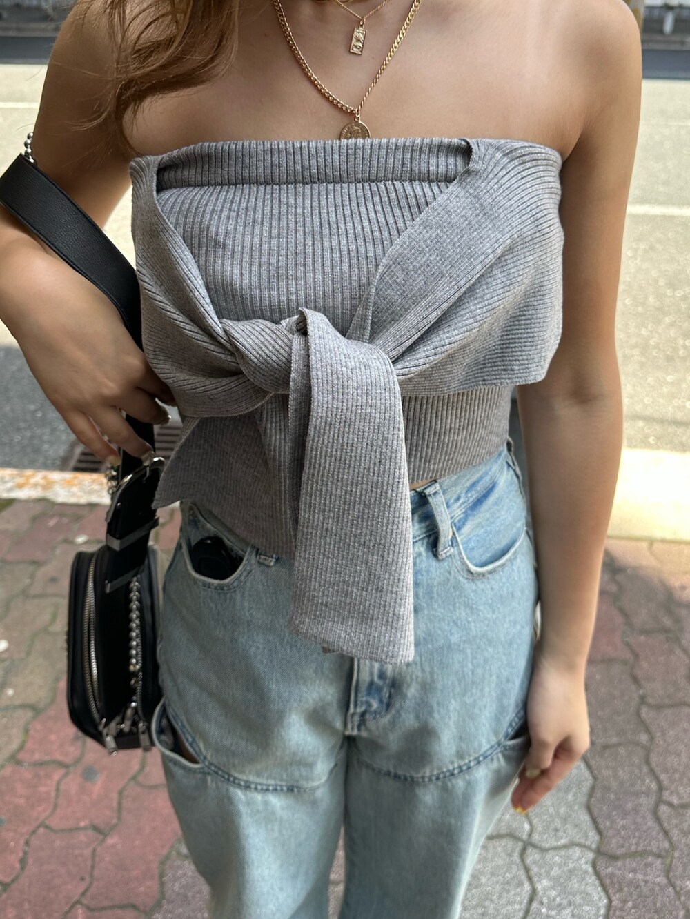 ブラック系のサンダル、ブラック系のショルダーバッグ、グレー系のチューブトップを着用したレディースの春コーディネートの5枚目の写真