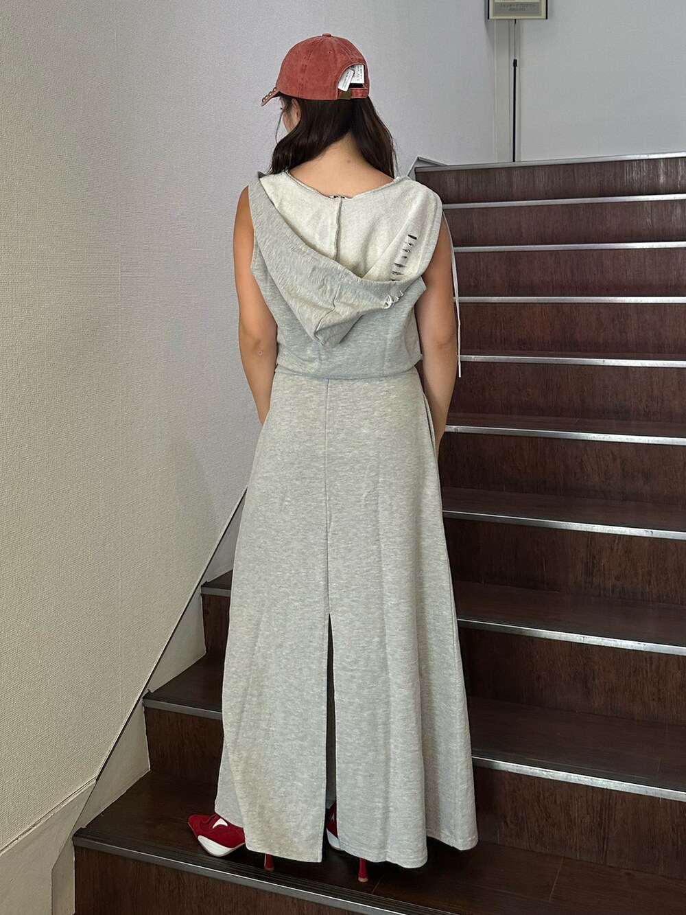 グレー系のワンピース、レッド系のパンプス、レッド系のキャップを着用したレディースの夏コーディネートの3枚目の写真