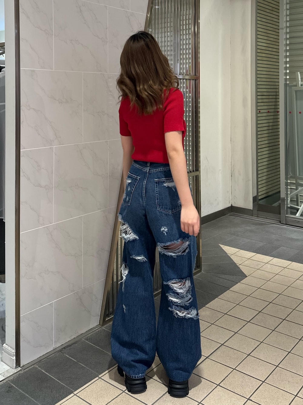 ブルー系のデニムパンツ、ブラック系のサンダル、レッド系のTシャツ/カットソーを着用したレディースの春コーディネートの3枚目の写真