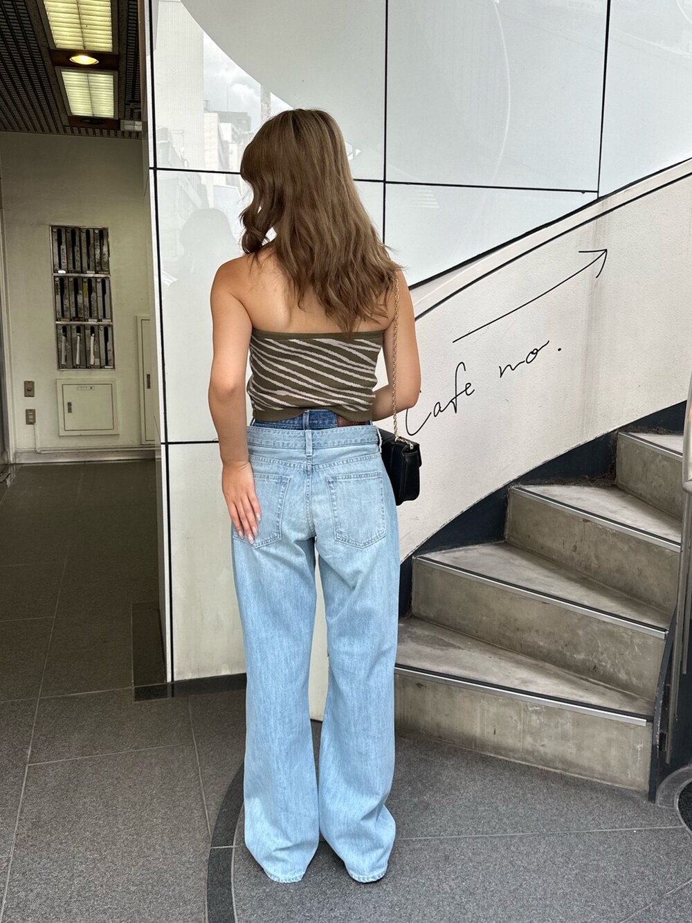 ブルー系のデニムパンツ、グリーン系のチューブトップ、ブラック系のショルダーバッグを着用したレディースの夏コーディネートの2枚目の写真