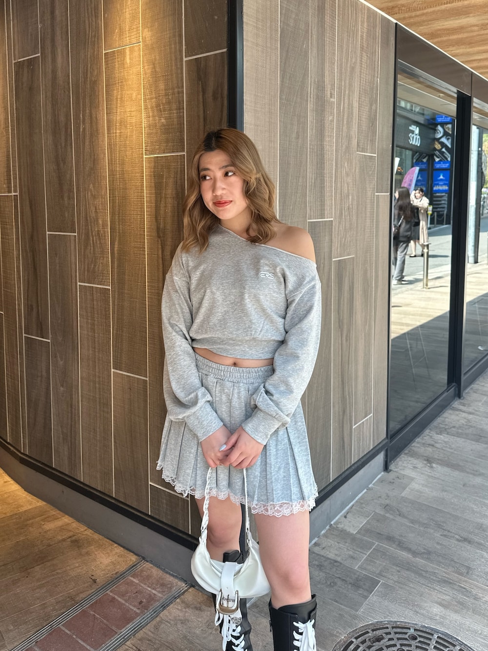 ホワイト系のショルダーバッグ、ブラック系のブーツ、グレー系のスウェットを着用したレディースの春コーディネートの5枚目の写真