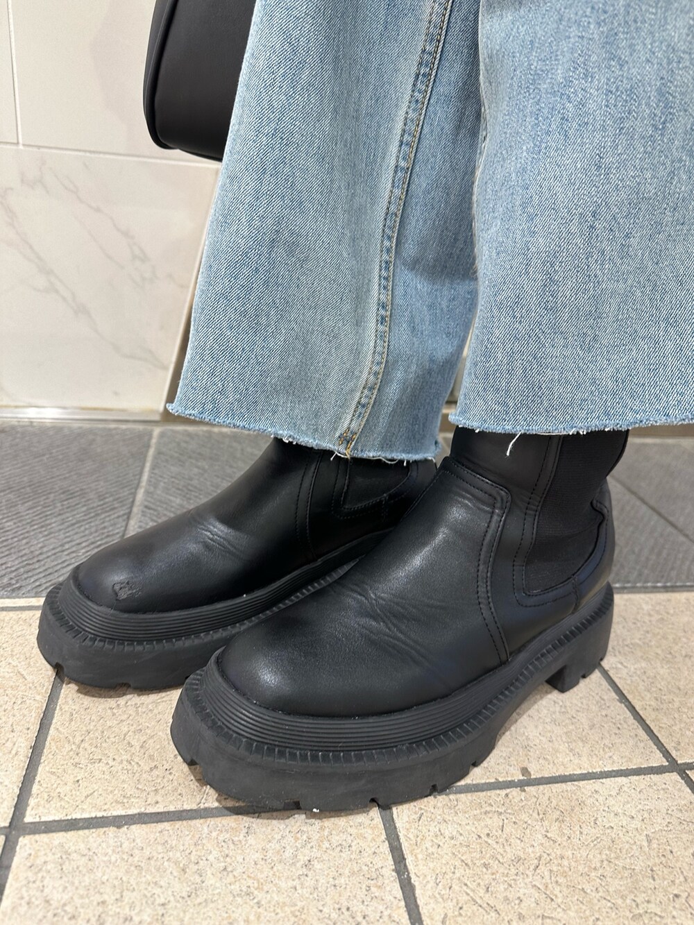 ブラック系のハンドバッグ、ブルー系のニット/セーター、ブルー系のデニムパンツを着用したレディースの冬コーディネートの7枚目の写真