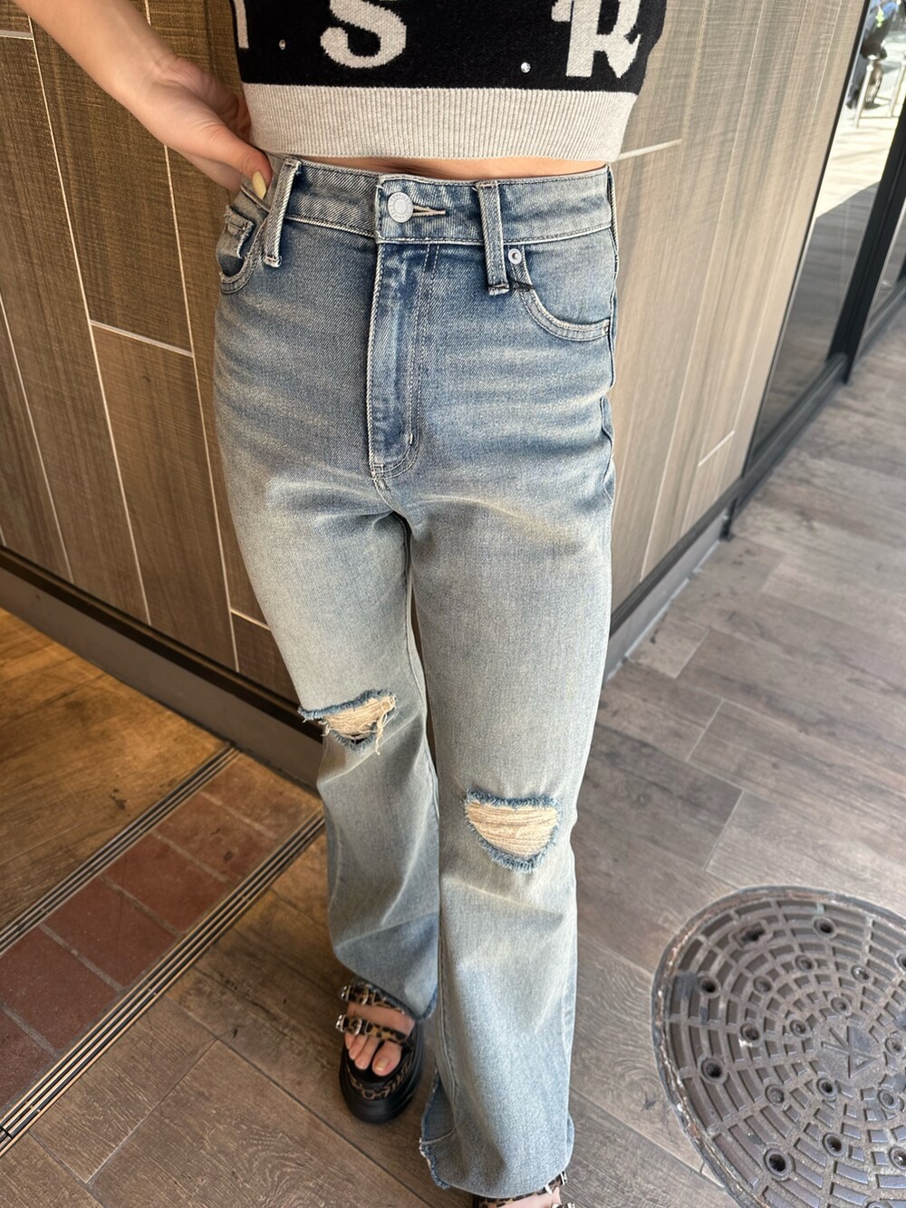 ブラック系のニット/セーター、ブルー系のデニムパンツ、その他のサンダルを着用したレディースの春コーディネートの7枚目の写真