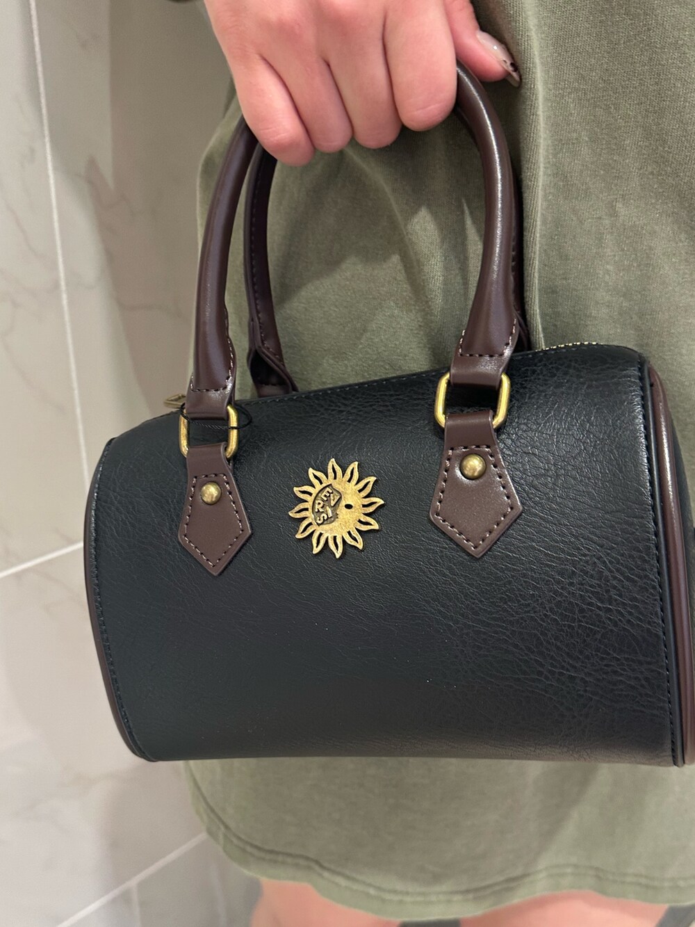 ブラック系のショルダーバッグ、ブラウン系のブーツ、グリーン系のTシャツ/カットソーを着用したレディースの春コーディネートの6枚目の写真