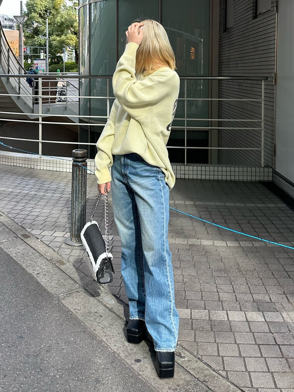 イエロー系のニット/セーター、ブルー系のデニムパンツ、ブラック系のショルダーバッグを着用したレディースの冬コーディネートの3枚目の写真