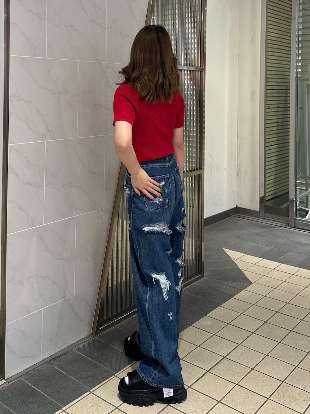 ブルー系のデニムパンツ、ブラック系のサンダル、レッド系のTシャツ/カットソーを着用したレディースの春コーディネートの2枚目の写真