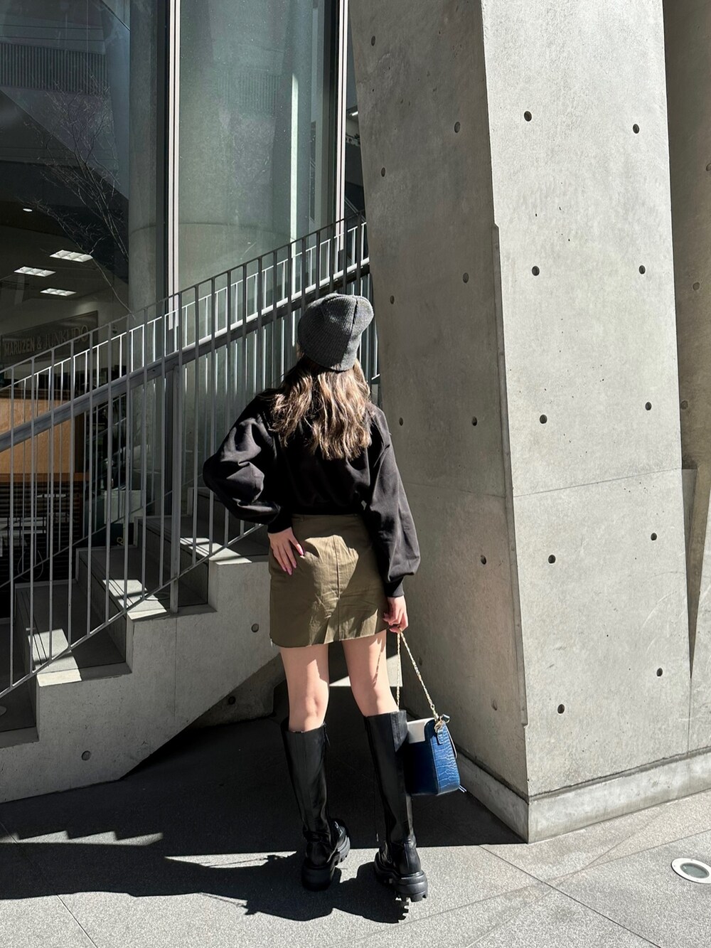 ブラック系のスウェット、ブラック系のブーツ、ブルー系のショルダーバッグを着用したレディースの冬コーディネートの2枚目の写真