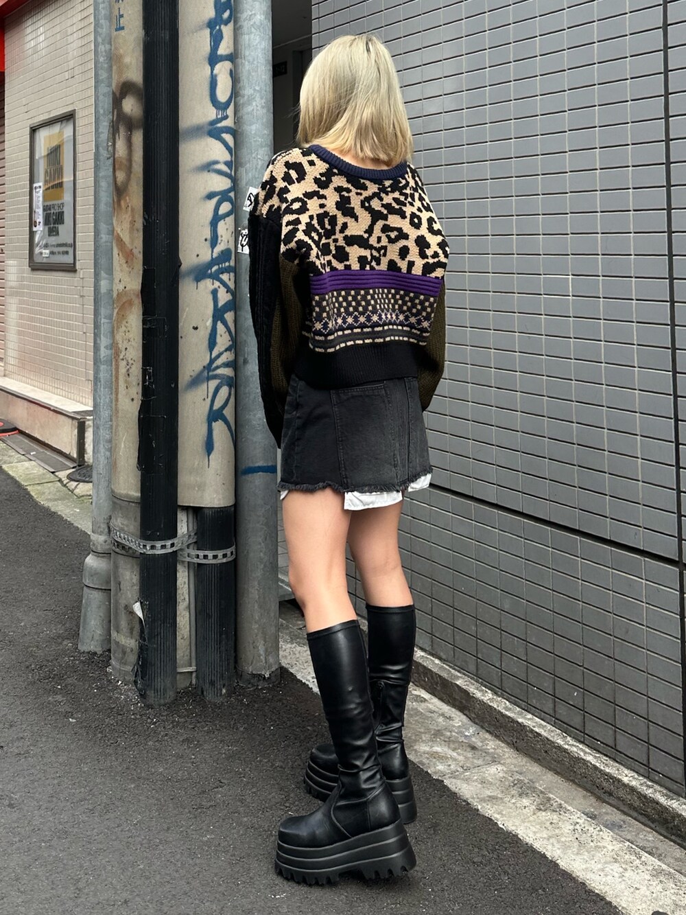 ブラック系のブーツ、ベージュ系のニット/セーター、ブラック系のデニムスカートを着用したレディースの冬コーディネートの2枚目の写真