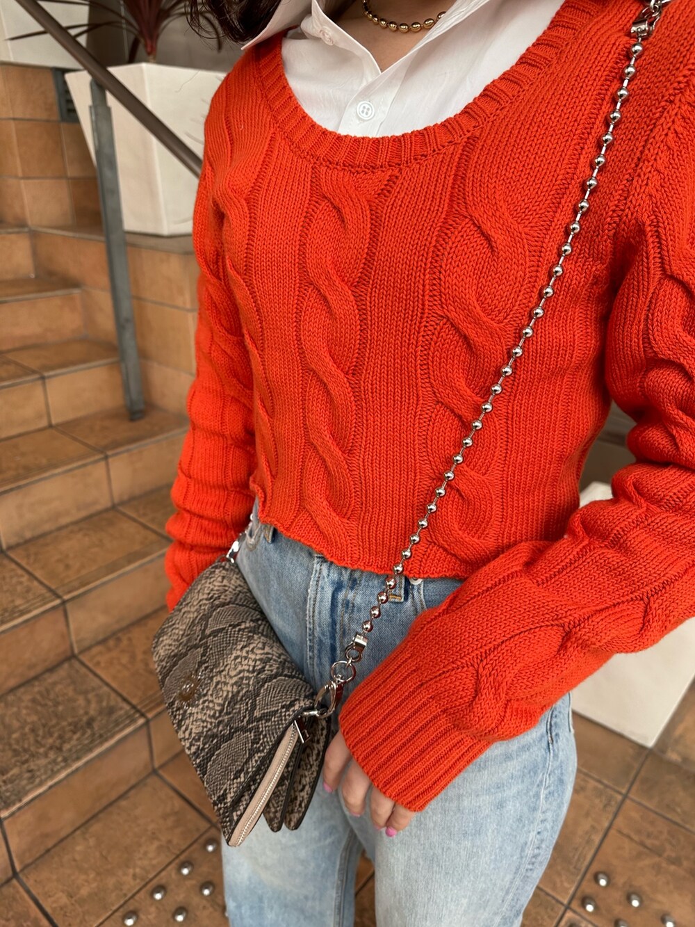 オレンジ系のカーディガン/ボレロ、ホワイト系のシャツ/ブラウス、ブルー系のデニムパンツを着用したレディースの冬コーディネートの5枚目の写真