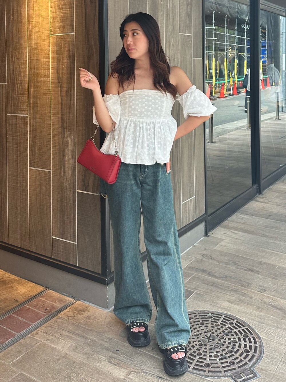 ブルー系のデニムパンツ、ホワイト系のシャツ/ブラウス、レッド系のショルダーバッグを着用したレディースの夏コーディネートの2枚目の写真