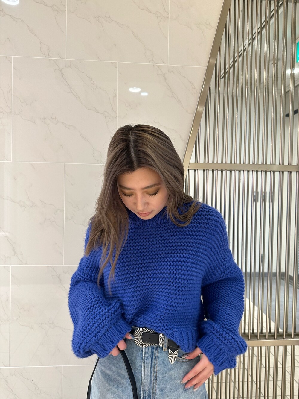 ブラック系のハンドバッグ、ブルー系のニット/セーター、ブルー系のデニムパンツを着用したレディースの冬コーディネートの3枚目の写真