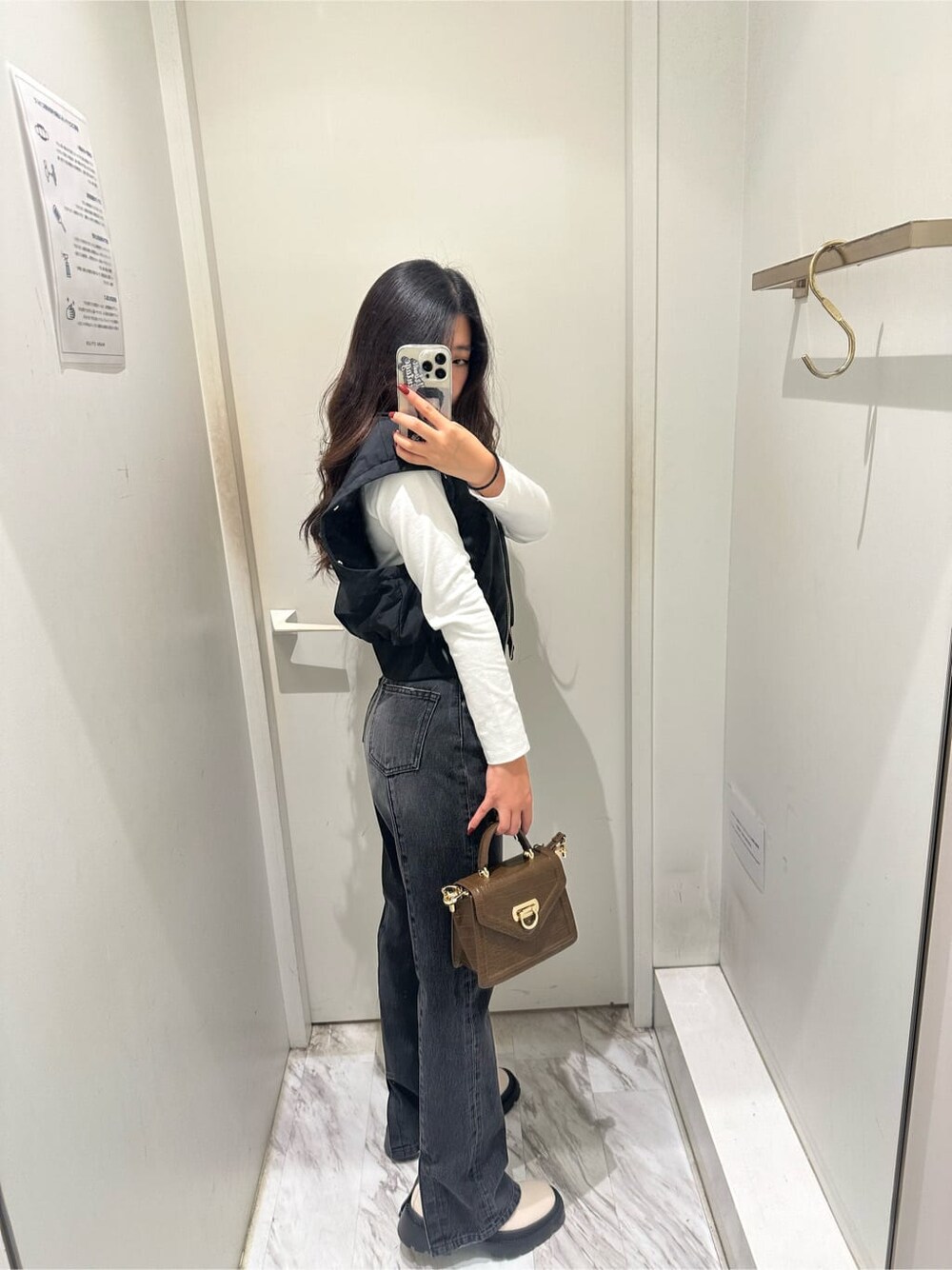 ブラック系のMA-1、ブラウン系のハンドバッグ、ブラック系のデニムパンツを着用したレディースの秋コーディネートの5枚目の写真