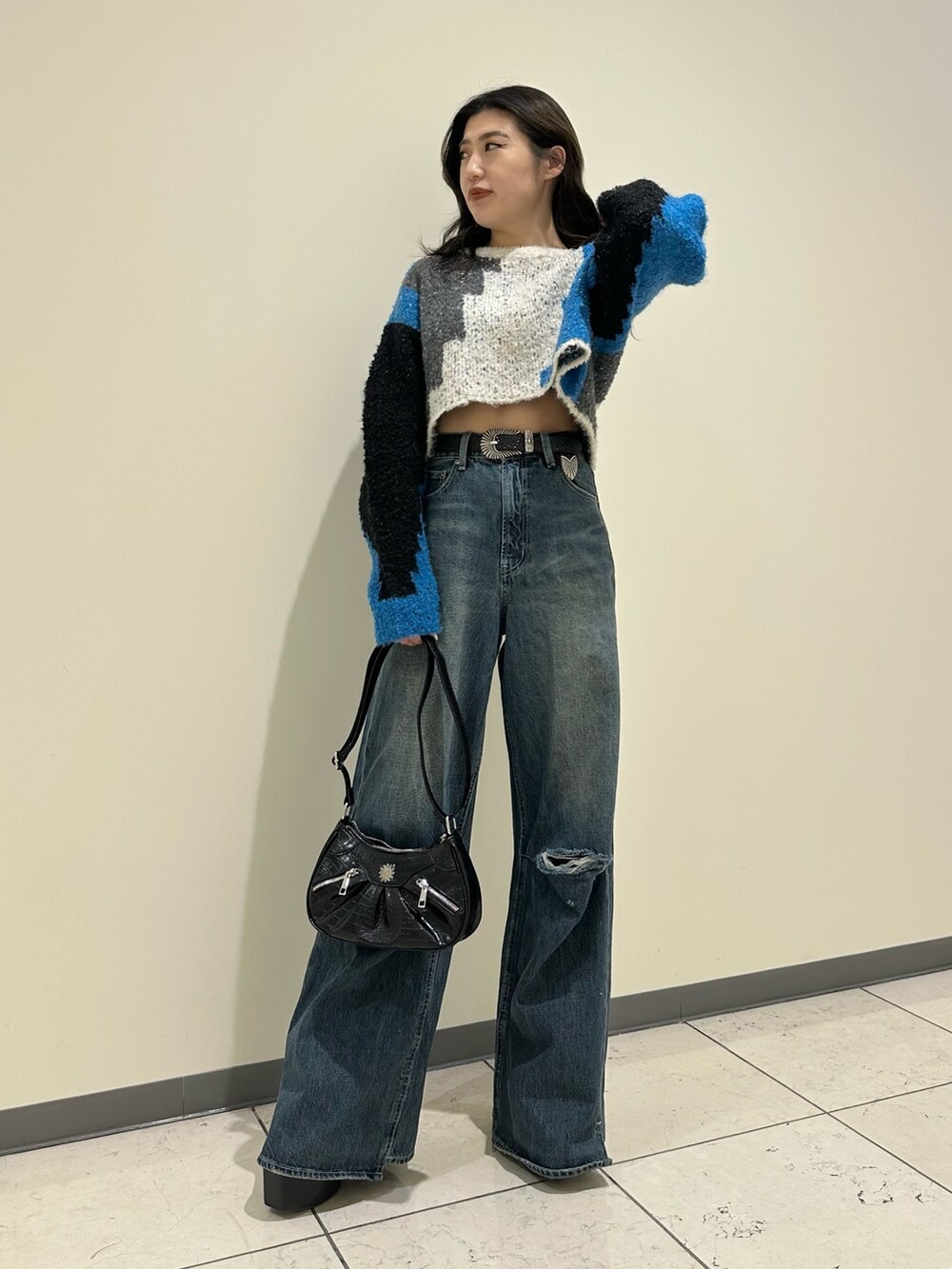 ブルー系のデニムパンツ、ブラック系のショルダーバッグ、ブラック系のブーツを着用したレディースの冬コーディネートの2枚目の写真